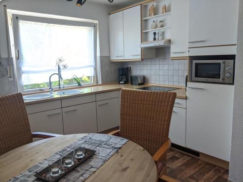 a kitchen with a table and a sink and a microwave at FeWo Wiesenallee OG in Geeste