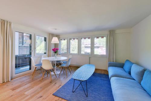 a living room with a blue couch and a table at Ferienlenk Mountain Village in Lenk