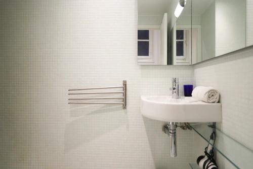 une salle de bain blanche avec un lavabo et un miroir dans l'établissement Paris - Tournelles - Place des Vosges, à Paris