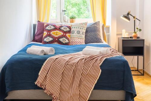 sypialnia z niebieskim łóżkiem z poduszkami i oknem w obiekcie Rent like home - Smolna 8 w Warszawie
