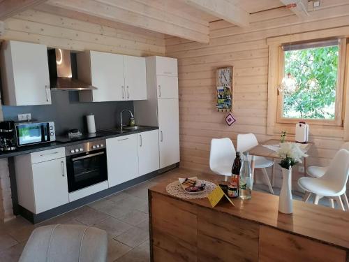 a kitchen with white cabinets and a table with chairs at Blockbohlenhaus-Steiner-Lodge in Steinen