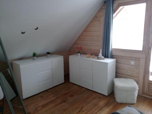 a attic room with two white cabinets and a window at Blockbohlenhaus-Steiner-Lodge in Steinen