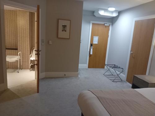 a room with a bed and a hallway with a door at Holiday Inn Dumfries by IHG in Dumfries