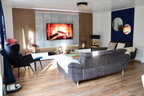 een woonkamer met een grijze bank en een open haard bij Luxury Apartment near Munich Airport - Therme ED - Parking in Berglern