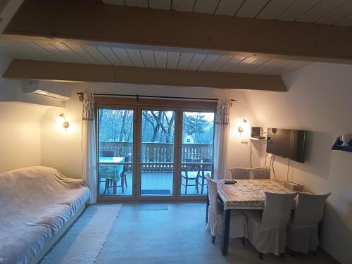 1 dormitorio con cama, mesa y balcón en Őzike-Lak a Börzsönyben, en Kismaros