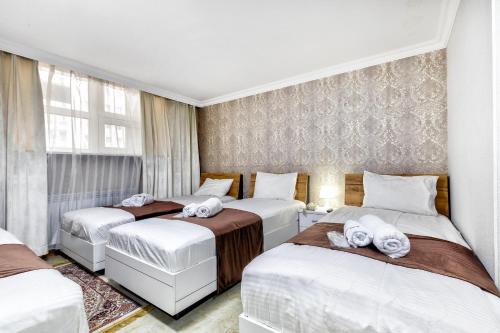 Hotel Bed and Breakfast في أستانا: غرفة نوم بثلاث اسرة عليها مناشف