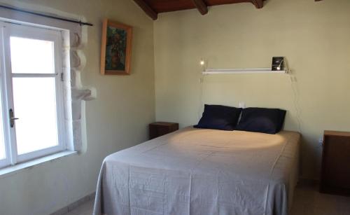a bedroom with a bed with blue pillows and a window at Villa Arismari - Kokkino Chorio in Chania Town
