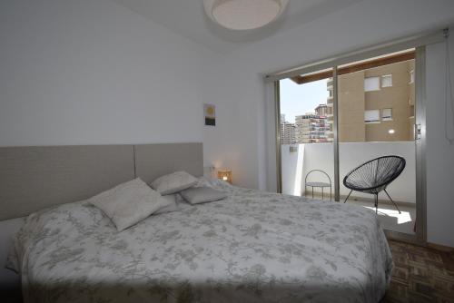 1 dormitorio con 1 cama y ventana con silla en Pdo. Mediterráneo - Fincas Arena, en Benidorm