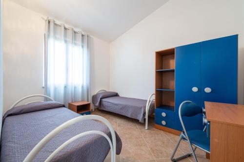 1 dormitorio con 1 cama azul, escritorio y 1 cama en Is Lais appartamento 2, en Masainas