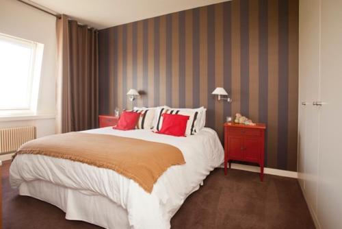 une chambre avec un grand lit avec des oreillers rouges dans l'établissement Biarritz - le Regina - proche phare, à Biarritz