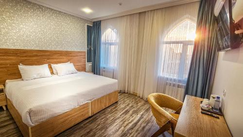 a bedroom with a bed and a desk and a table at Hotel Bankir Khiva in Khiva