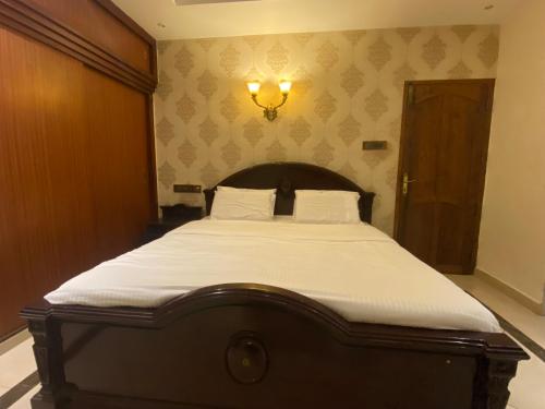 a large bed in a bedroom with a light on the wall at Queen's in Trivandrum