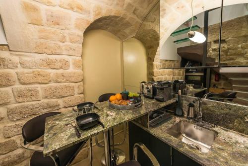 une cuisine avec un évier et un comptoir avec des chaises dans l'établissement Le Marais - Place des Vosges - Tournelles 86, à Paris