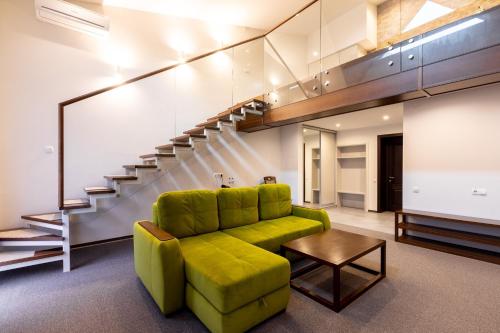 a living room with a green couch and stairs at Hotel-Restaurant Complex Vensky in Brovary