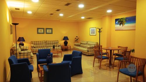 a waiting room with couches and a table and chairs at Hotel Oca Vermar in Aios
