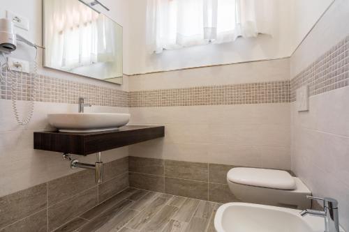 a bathroom with a sink and a toilet and a mirror at Hotel Il Buongustaio in Massa