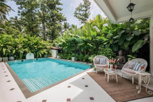a swimming pool with two chairs and a table next to a house at LohonoStays Castello Villa 5 in Vagator