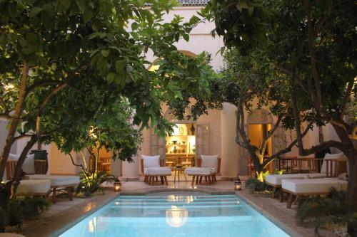 una piscina en medio de un patio con árboles en Riad Emberiza Sahari, en Marrakech