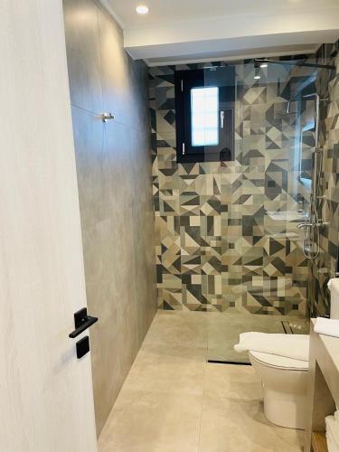 a bathroom with a toilet and a glass shower at GEMINI VILLAS NIKITI in Nikiti