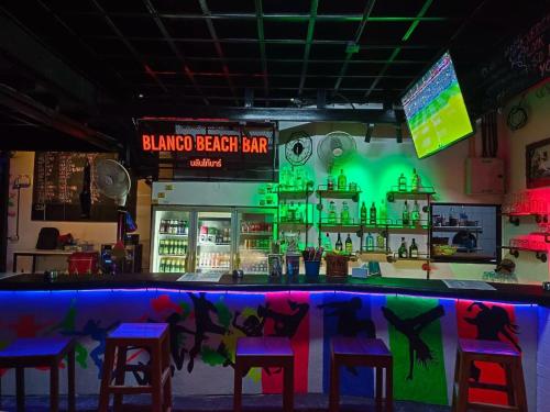 a bar with stools and a bar with green lights at Blanco Beach Bar Hostel in Phi Phi Islands