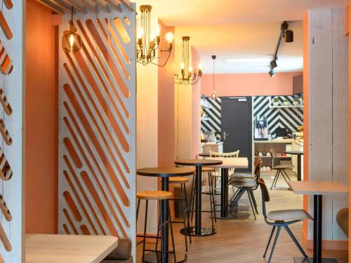 パリにあるイビス パリ ツアー モンパルナス 15区のオレンジ色の壁とテーブルとスツールが特徴のレストラン