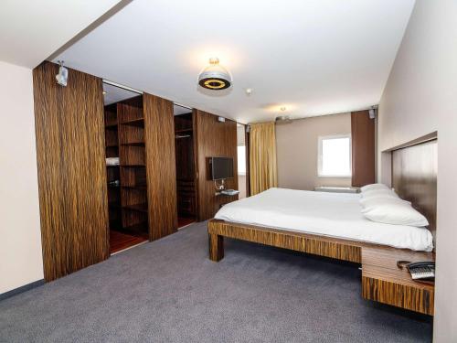 um quarto com uma grande cama branca e armários de madeira em Ibis Praha Old Town em Praga