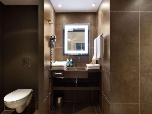 ein Badezimmer mit einem Waschbecken, einem WC und einem Spiegel in der Unterkunft Novotel Moscow City in Moskau