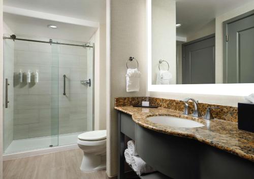 a bathroom with a toilet and a sink and a shower at Embassy Suites Tucson - Paloma Village in Tucson