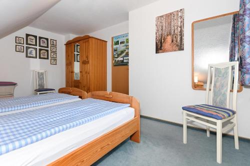 um quarto com uma cama e uma cadeira em Ferienhaus Dat Krebs Huus em Dornumersiel