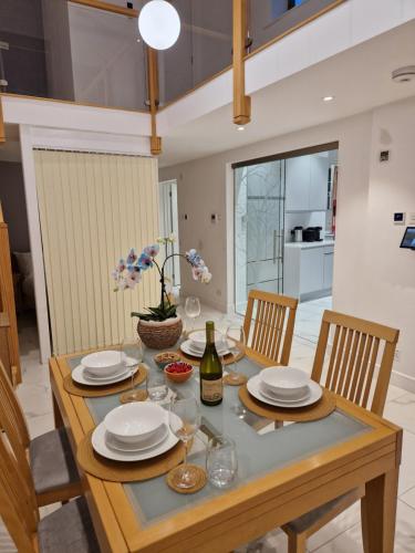 a dining room table with plates and a bottle of wine at The Old Hay Store, Ely in Ely