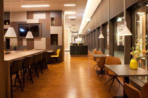 a restaurant with a long bar with chairs and tables at Hampton By Hilton Munich City Center East in Munich