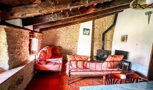 una sala de estar con muebles de color rojo y una pared de piedra. en La Fonda de Xiva en Chiva de Morella
