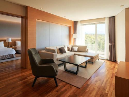 Mercure Ambassador Jeju في سيوجويبو: غرفة معيشة مع أريكة وكرسي وطاولة