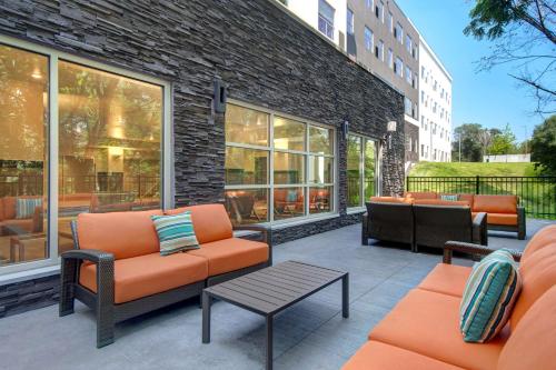 eine Terrasse mit orangefarbenen Stühlen und Tischen sowie ein Gebäude in der Unterkunft Hyatt House Mall Of America Msp Airport in Bloomington