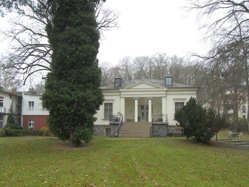 une grande maison blanche avec un arbre en face dans l'établissement Tarnowskis Villa Seeblick, nur 50m zum Strand, WLAN inkl, à Neuhof