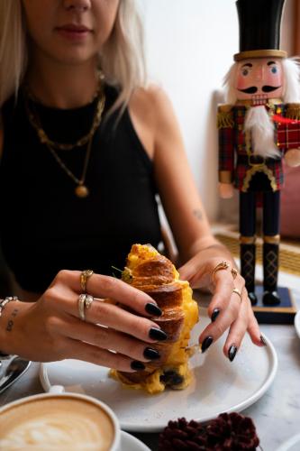 a woman sitting at a table with a sandwich on a plate at Hotel Babula am Augarten in Vienna