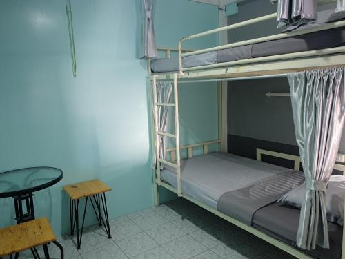 a room with two bunk beds and a table at U2 & i-smile Hostel in Chiang Mai