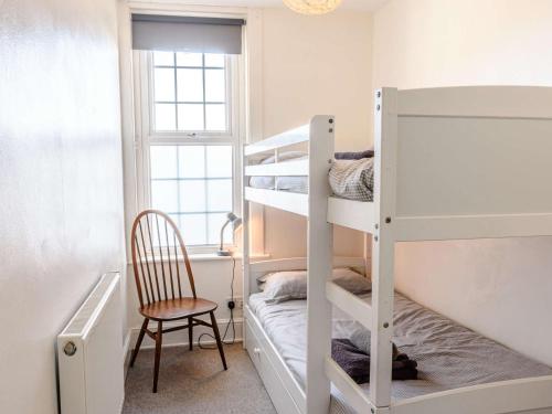 um quarto com beliches, uma cadeira e uma janela em 3 Bed in Shanklin 49398 em Shanklin