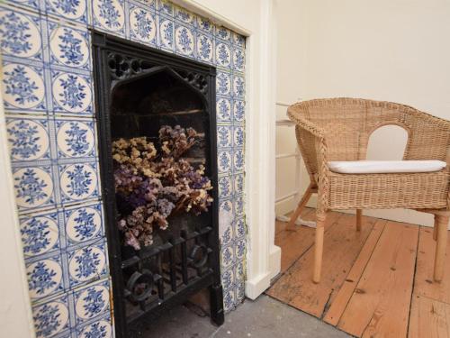 una chimenea con azulejos azules y blancos y una silla en 4 bed in Lyndhurst 57407, en Lyndhurst