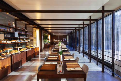 a dining room with long tables and a large window at UNA HOTELS One Siracusa in Siracusa