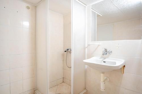 een witte badkamer met een wastafel en een douche bij Roubenka Muštelka in Rokytnice nad Jizerou