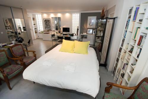 - une chambre avec un grand lit et 2 oreillers jaunes dans l'établissement Montmartre - Ruisseau - magnifique appartement artistique, à Paris