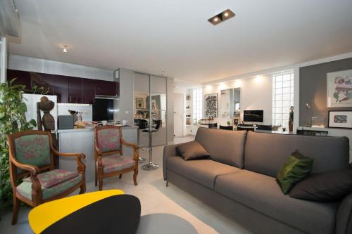 un salon avec un canapé et des chaises et une cuisine dans l'établissement Montmartre - Ruisseau - magnifique appartement artistique, à Paris