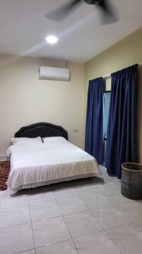 a bedroom with a large bed with blue curtains at The Backyard Cottage 168 in Keningau