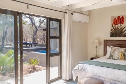 Un dormitorio con una cama y una puerta corrediza de vidrio. en The Aloes Bush Lodge, en Marloth Park