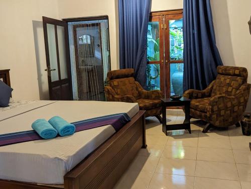 een slaapkamer met een bed met blauwe kussens en stoelen bij Ceyio traditional villa in Matara