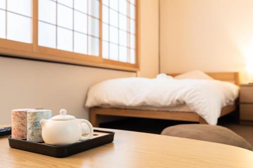 a tray with a tea kettle on a table with a bed at 鶴橋妙宅 in Osaka