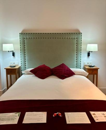 a bed with two red pillows and two certificates on it at Apartamentos Turísticos La Plaza in Chipiona