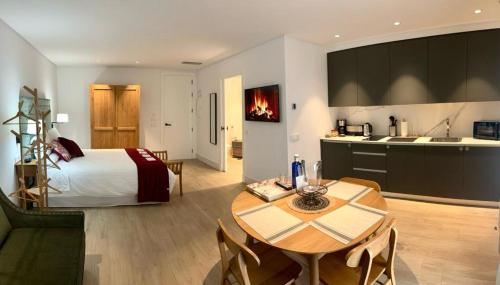 a bedroom with a bed and a table and a kitchen at Apartamentos Turísticos La Plaza in Chipiona