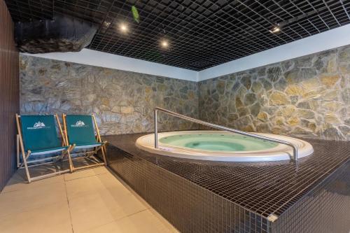 eine Whirlpool-Badewanne in einem Zimmer mit Stuhl in der Unterkunft Apartament basen sauna Revisit Szklarska in Szklarska Poręba